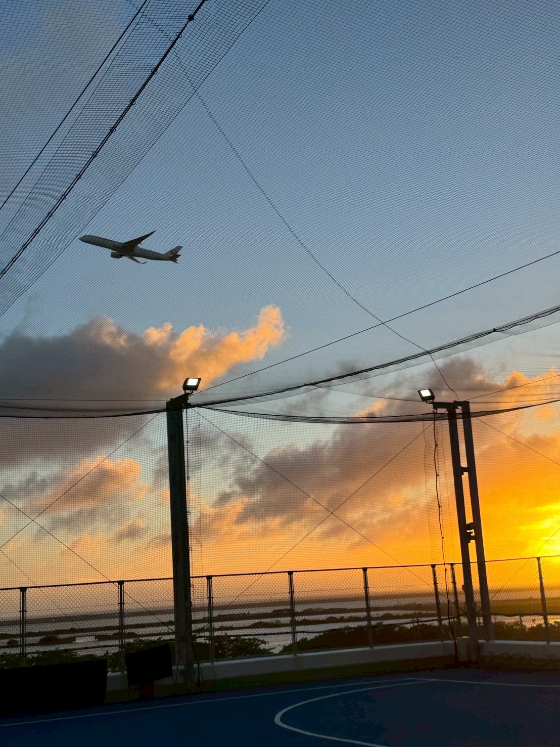 夕焼け空を飛ぶ飛行機とコートの照明